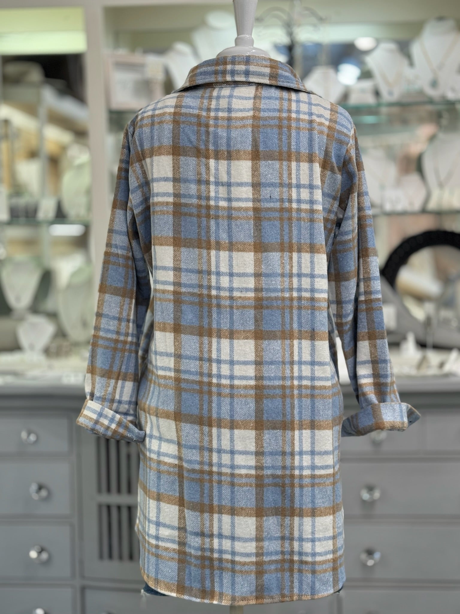 Back of women’s blue and camel plaid shacket, cozy button-up jacket.