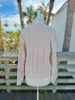 Back view Cable knit sweater in beige on a mannequin outdoors.