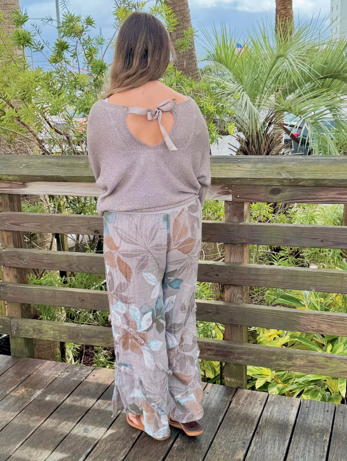 Back view of Briella taupe shimmer sweater showing ribbon bow detail and open-back design