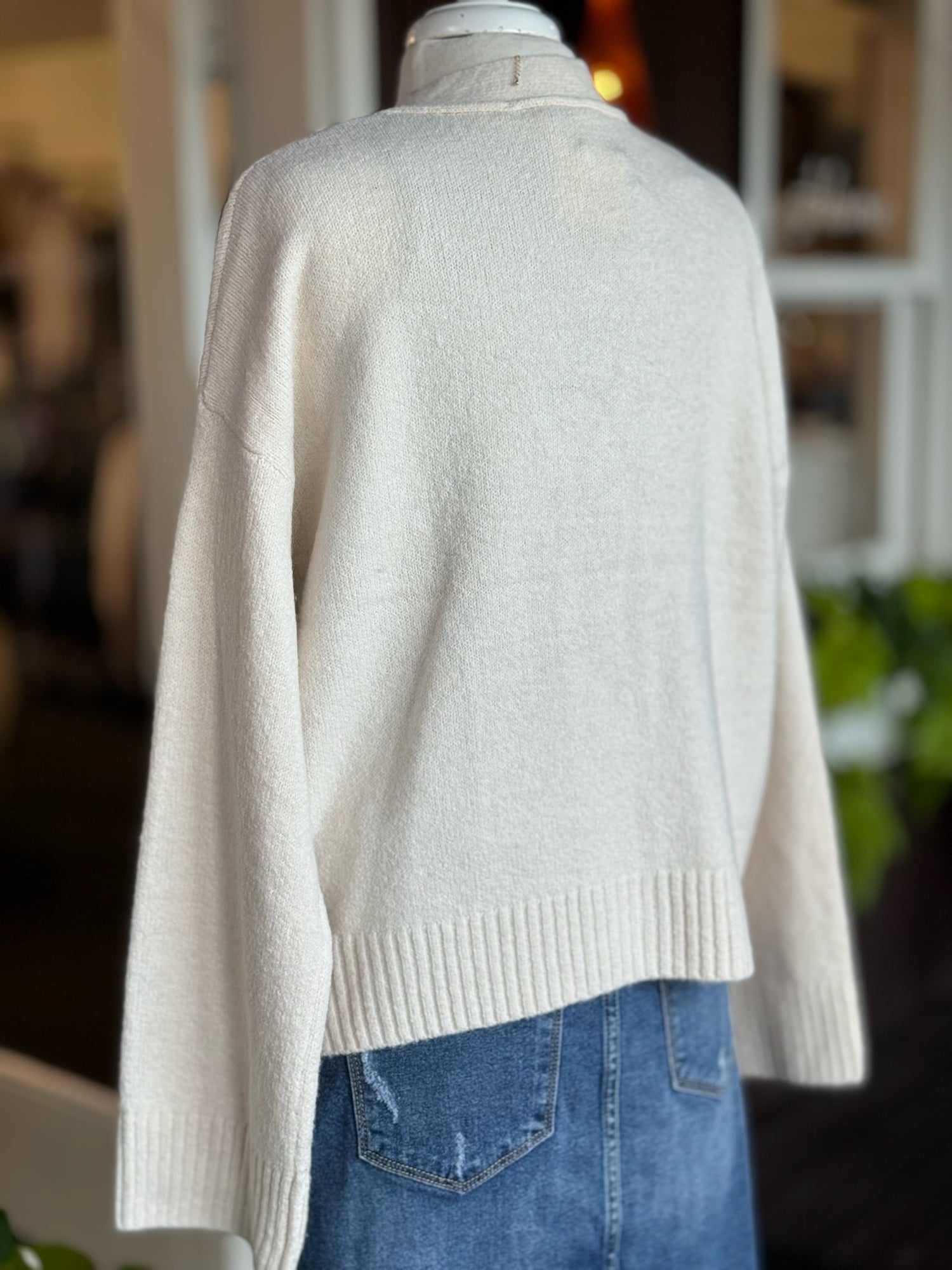 Back view of Jody Button Cardigan in cream showing cozy knit fabric and ribbed hem.