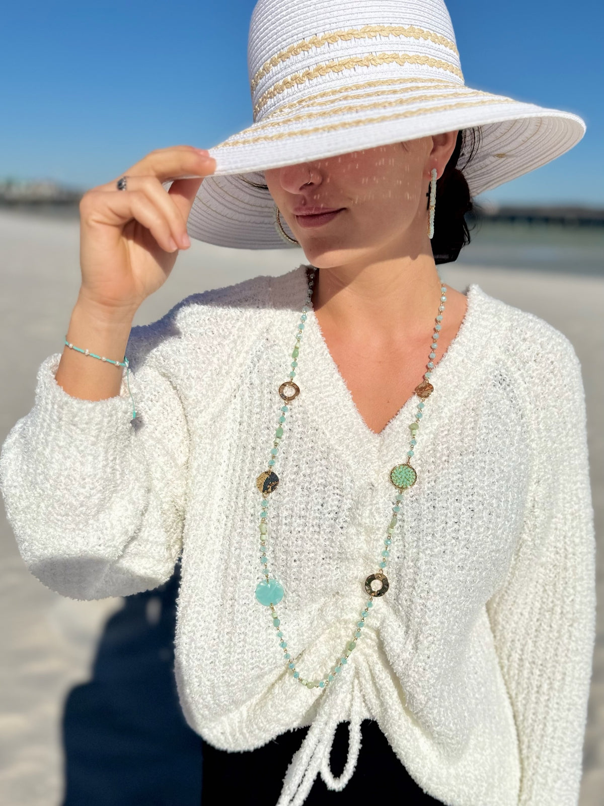 Beatrix Necklace in Teal styled for the beach with a lightweight sweater and sun hat