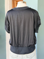 Black blouse on a mannequin against a light blue wall