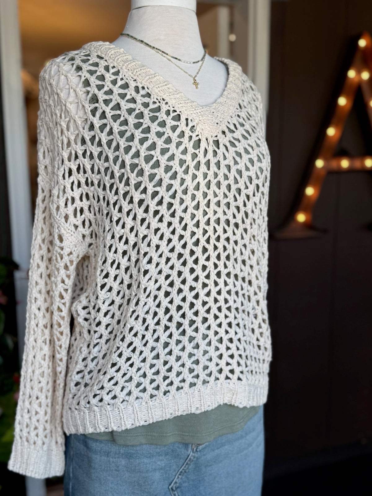Bree Open Knit Sweater in beige with a V-neckline, relaxed fit and airy open-knit texture, layered over an olive tank at Ardor Boutique.