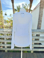 White open knit sweater on a mannequin outdoors back view with a long blue and gold necklace