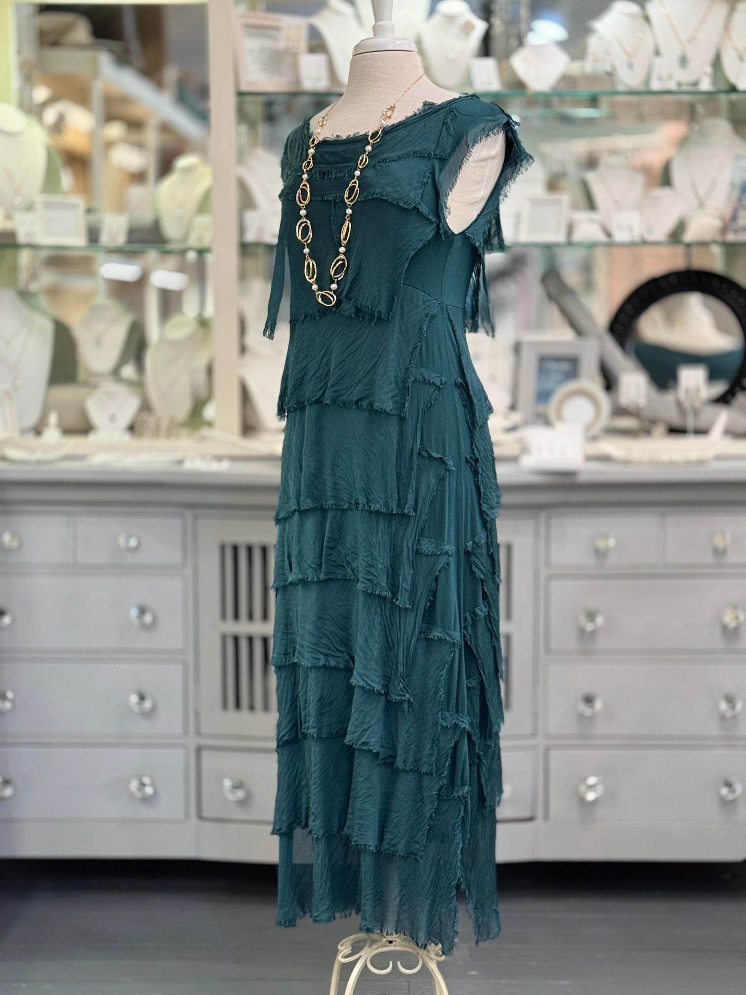 Detail of the layered silk tiers on the Briella Dress highlighting the lightweight texture and drape. Paired with long pearl and gold necklace