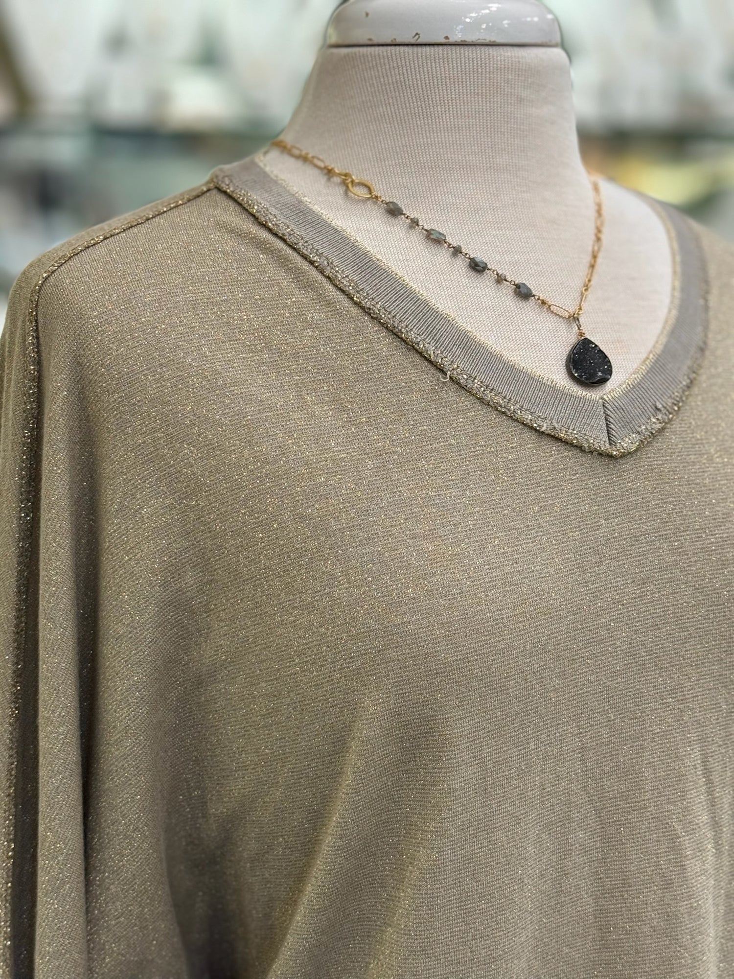 Close-up of the Celeste Top in mocha, showing the metallic-knit texture, ribbed V-neckline with soft frayed edging.