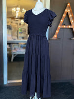 Navy maxi dress with a smocked bodice, V-neckline, ruffle short sleeves and a flowing tiered skirt at Ardor Boutique.