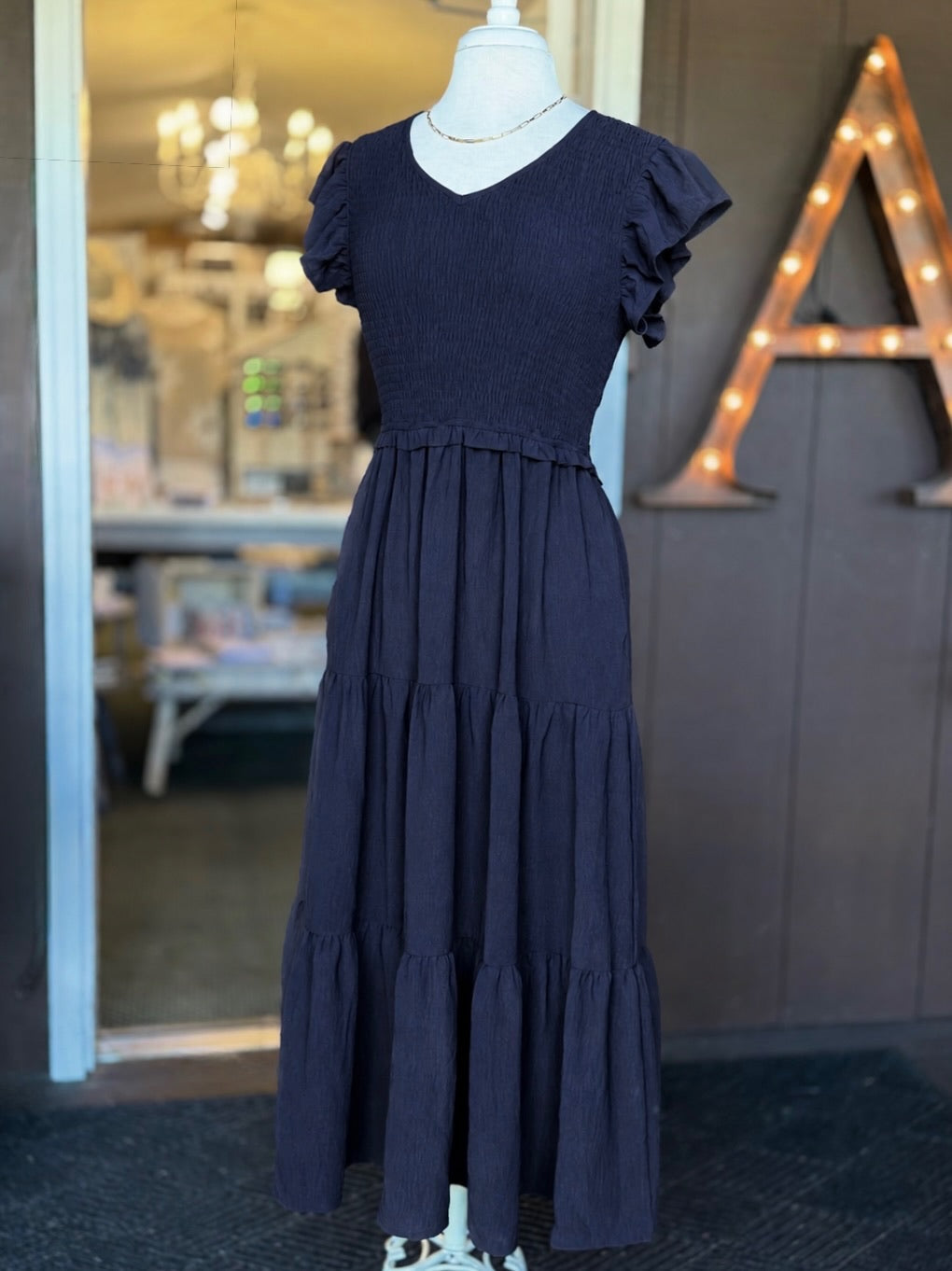 Navy maxi dress with a smocked bodice, V-neckline, ruffle short sleeves and a flowing tiered skirt at Ardor Boutique.