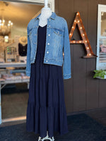 Navy maxi dress with a smocked bodice, V-neckline, ruffle short sleeves and a flowing tiered skirt paired with a jean jacket at Ardor Boutique.