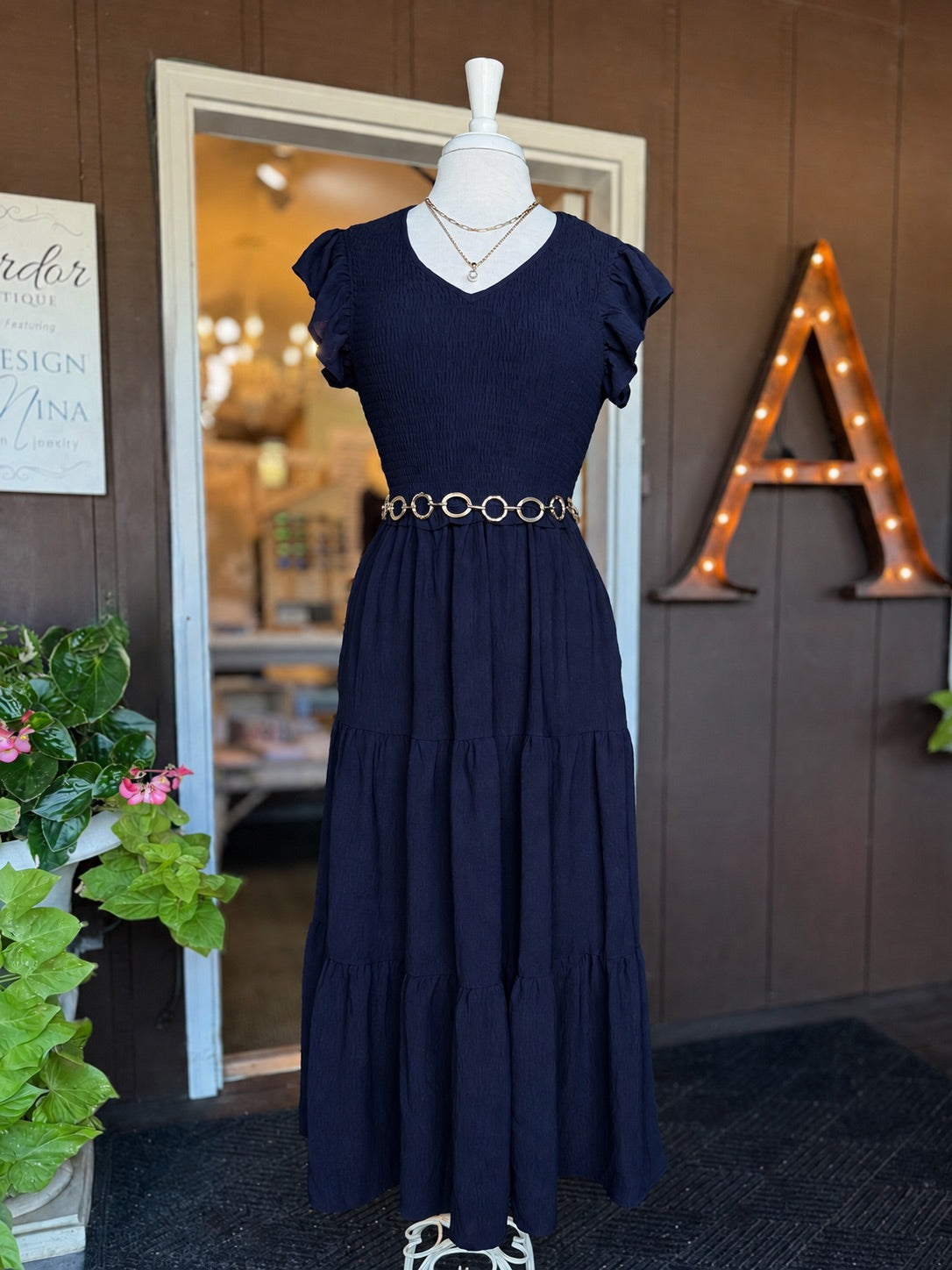 Navy maxi dress with a smocked bodice, V-neckline, ruffle short sleeves and a flowing tiered skirt at Ardor Boutique.