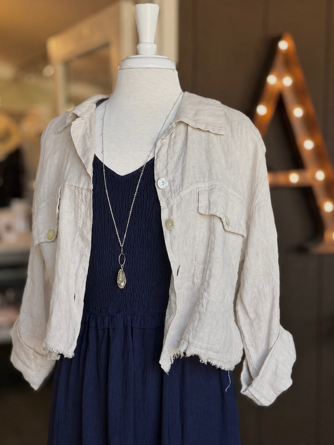Everly Dress in navy layered with a beige linen jacket and long silver pendant necklace at Ardor Boutique.