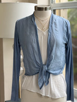 A blue silk cardigan with a V-neckline and long sleeves, displayed on a mannequin that is wearing a white top and has a necklace around its neck.