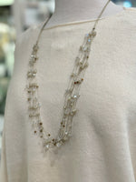 Close-up detail of cotton-acrylic knit fabric in cream reversible cropped sweater and necklace