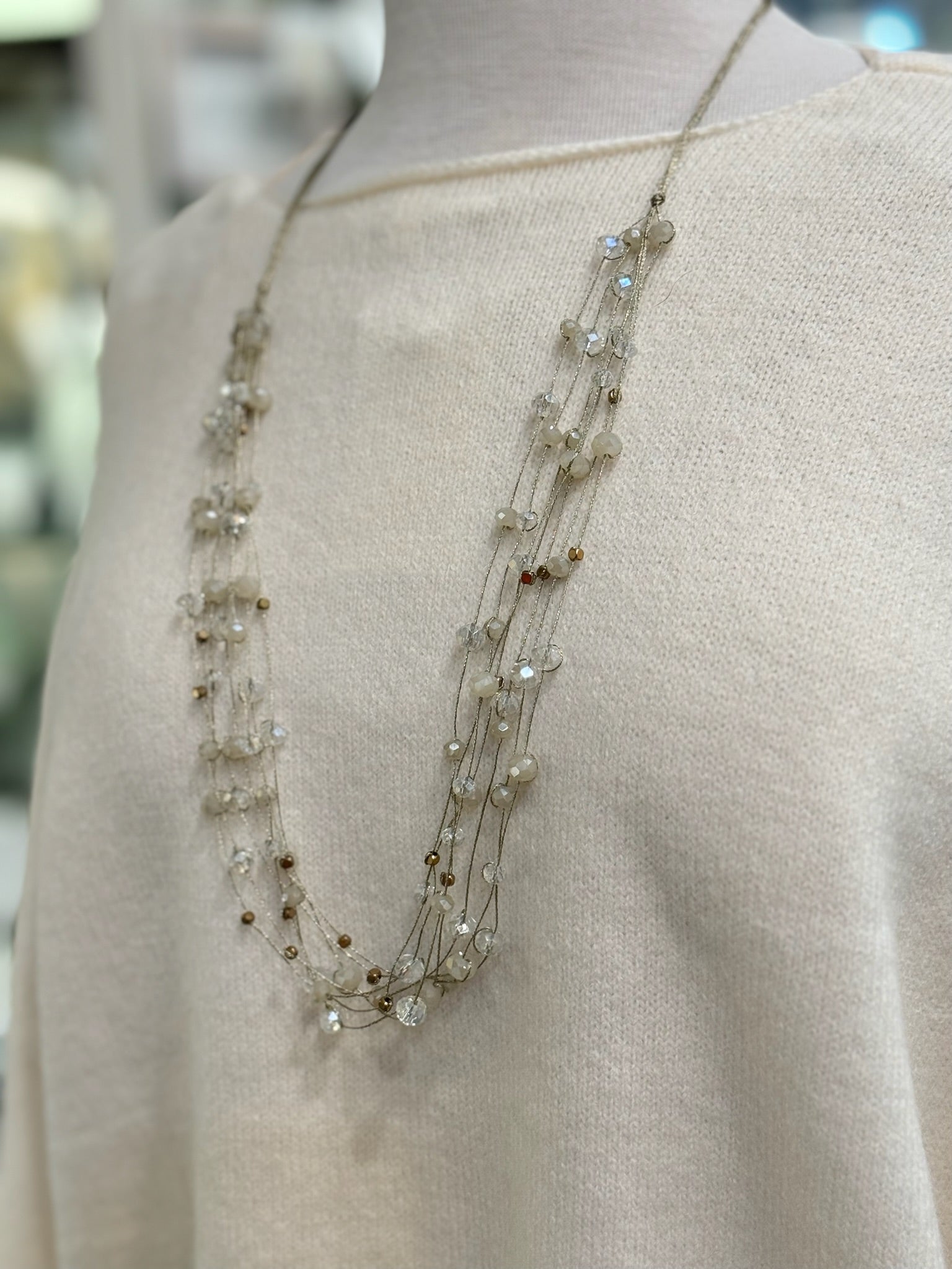 Close-up detail of cotton-acrylic knit fabric in cream reversible cropped sweater and necklace