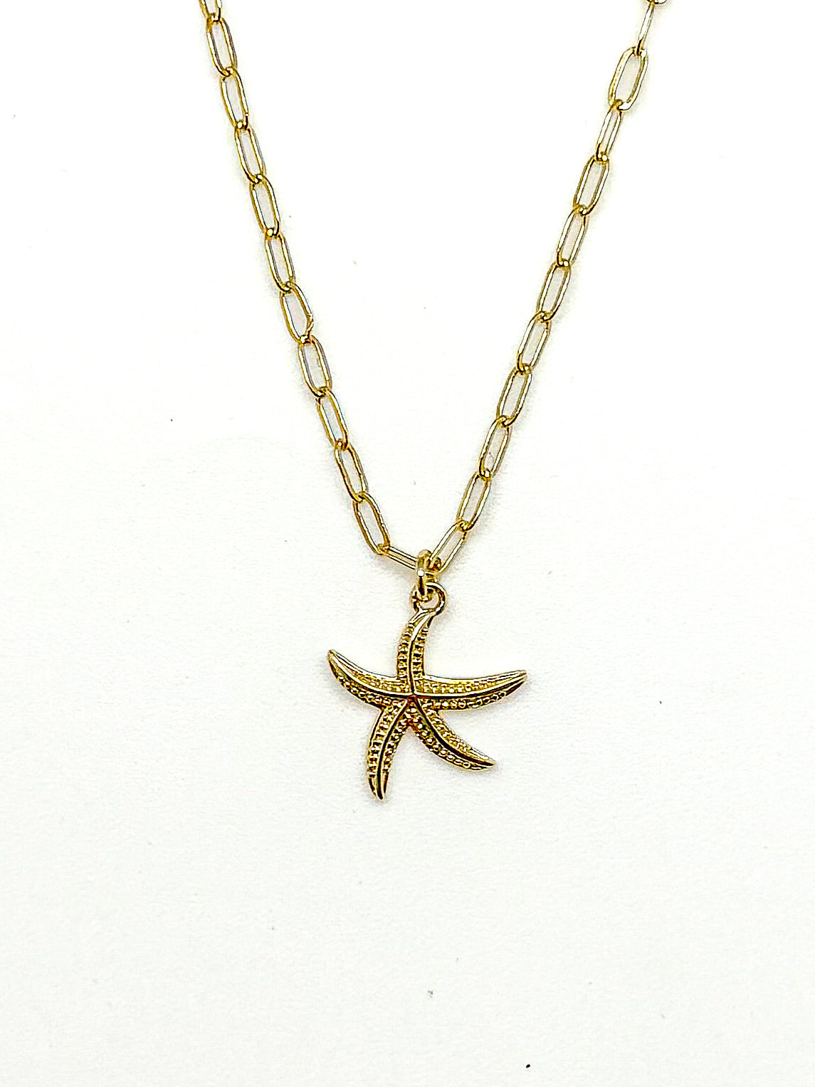 Gold starfish pendant necklace on a white background