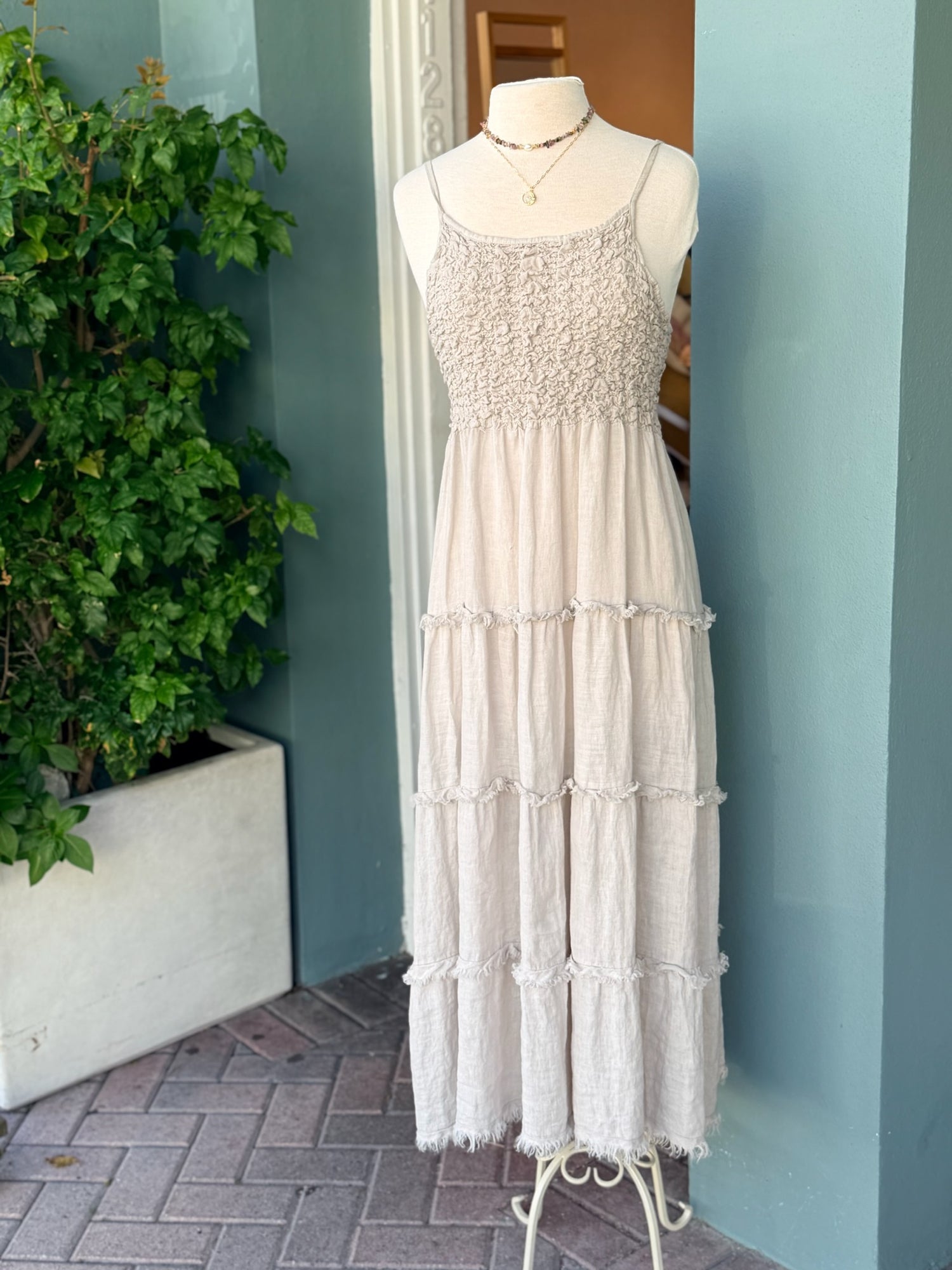 Cream sleeveless tiered midi dress with textured bodice displayed on mannequin