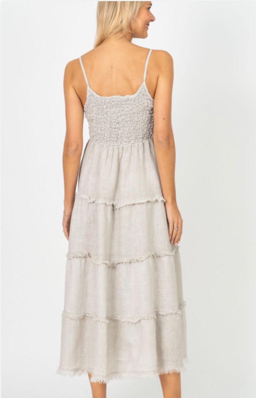 Cream sleeveless tiered midi dress with textured bodice shown from back on model