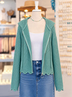 Kennedy Hoodie in teal featuring textured open knit, a full zipper with ring pull, hood with drawstrings, and cropped scalloped hem, styled with denim at Ardor Boutique.