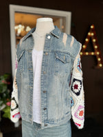 Front view of the Dahlia Granny Square Denim Jacket in Sunrise Ivory with light wash distressed denim, hand-crocheted multicolor granny square sleeves, chest pockets, and button front at Ardor Boutique.