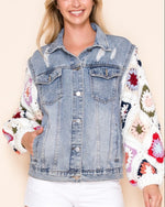 Dahlia Granny Square Denim Jacket in Sunrise Ivory shown on a model, featuring an oversized light wash denim body, distressed details, and colorful hand-crocheted sleeves.