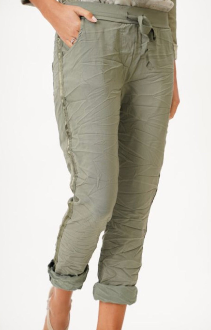 model wearing olive green crinkle jeggings with side stripe, front view.