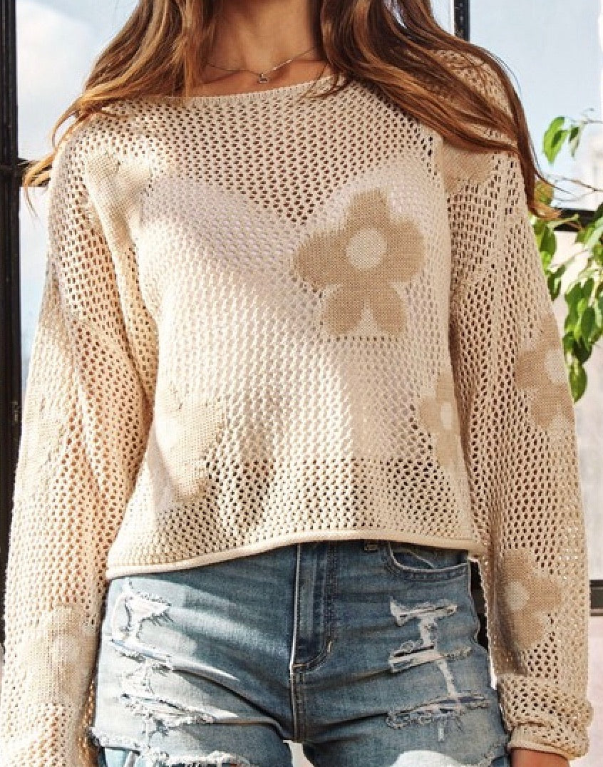 Close-up of the crochet texture and daisy flower design on the beige sweater from Ardor Boutique.