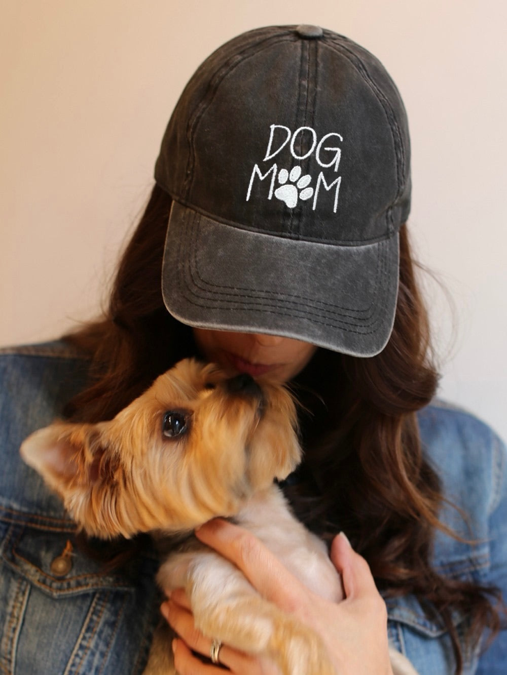 Woman wearing the Dog Mom Cap in black while holding her small dog