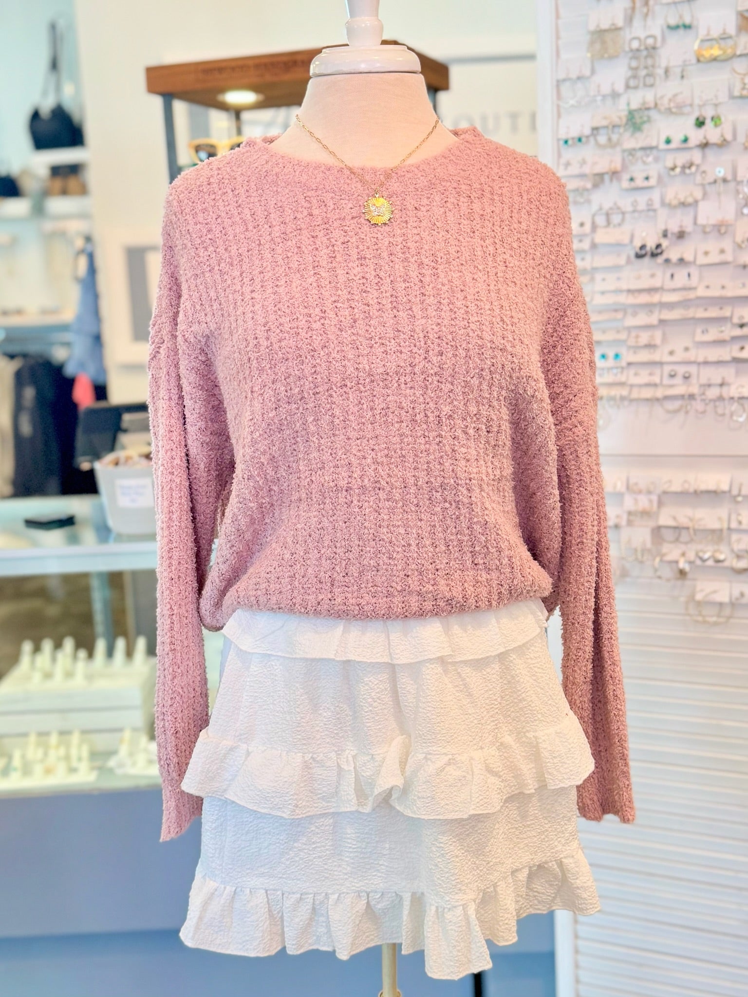 Mannequin wearing a pink sweater and white ruffled skirt in a store setting