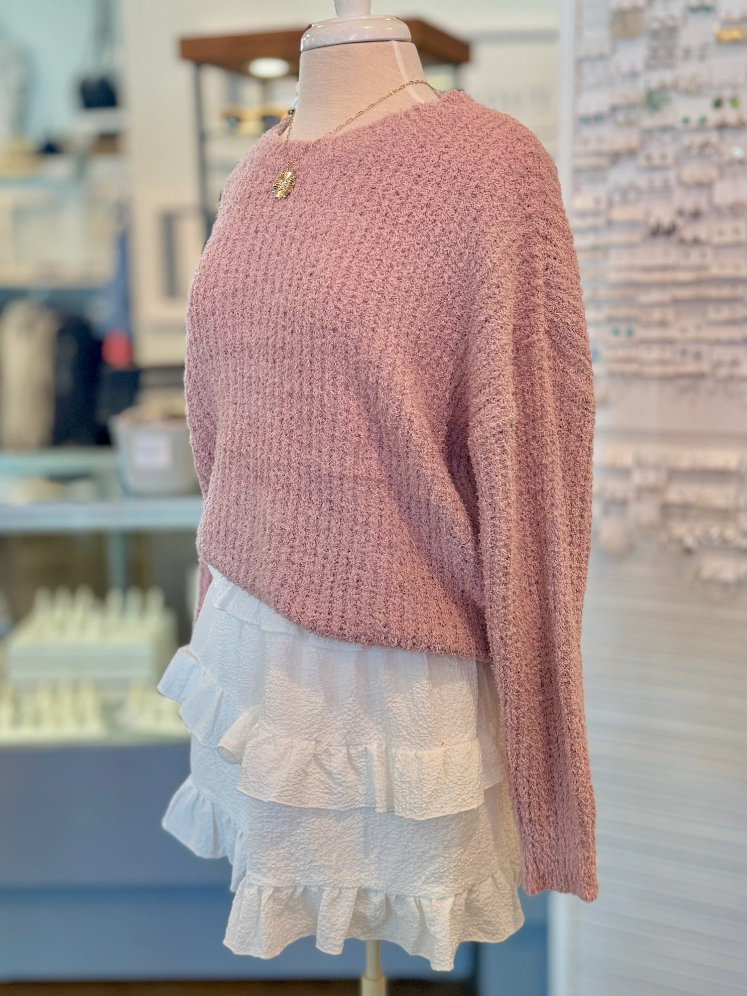 Mannequin wearing a pink sweater and white ruffle skirt in a store setting