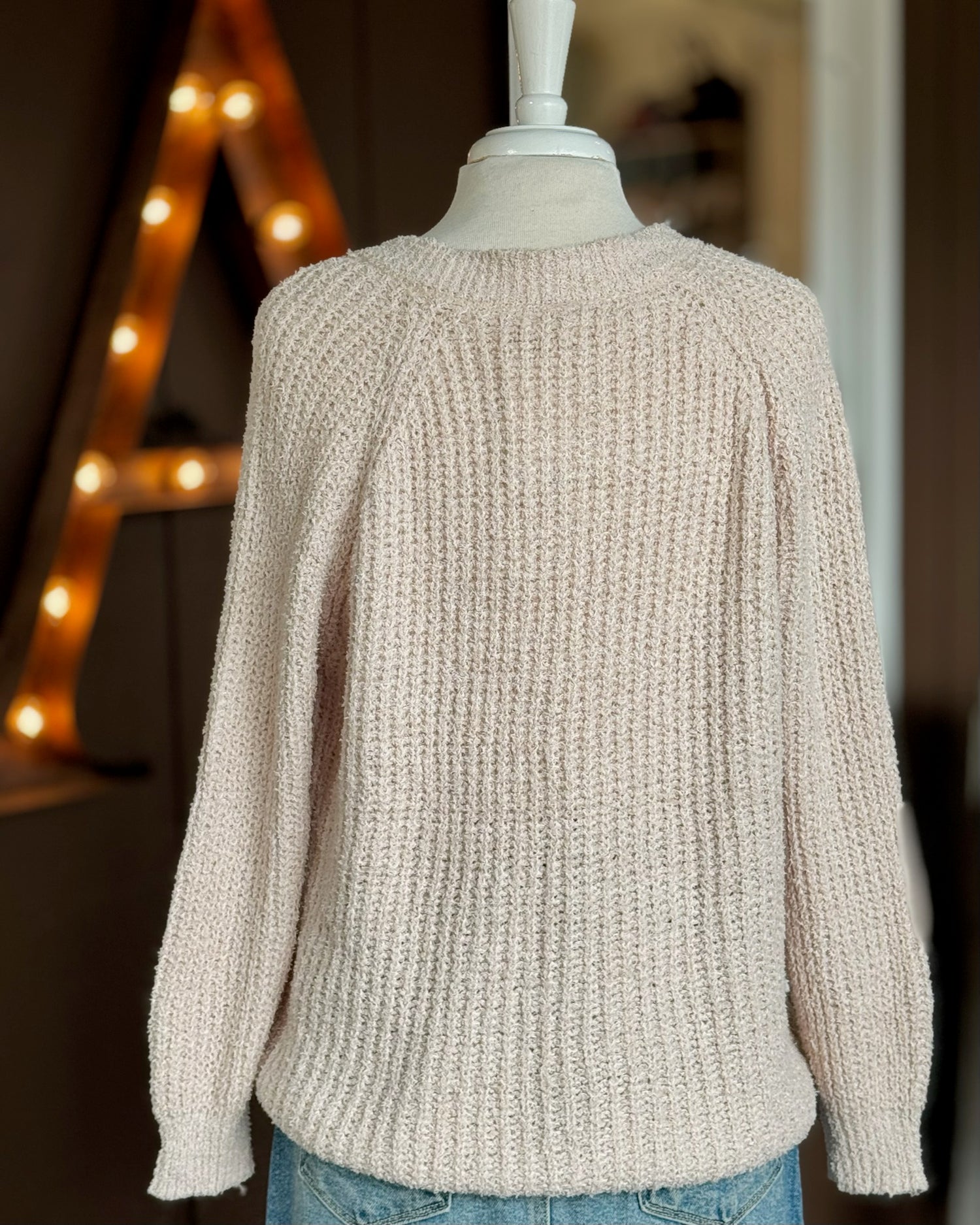 Back view of neutral textured sweater on a dress form showing relaxed fit in a soft waffle knit.