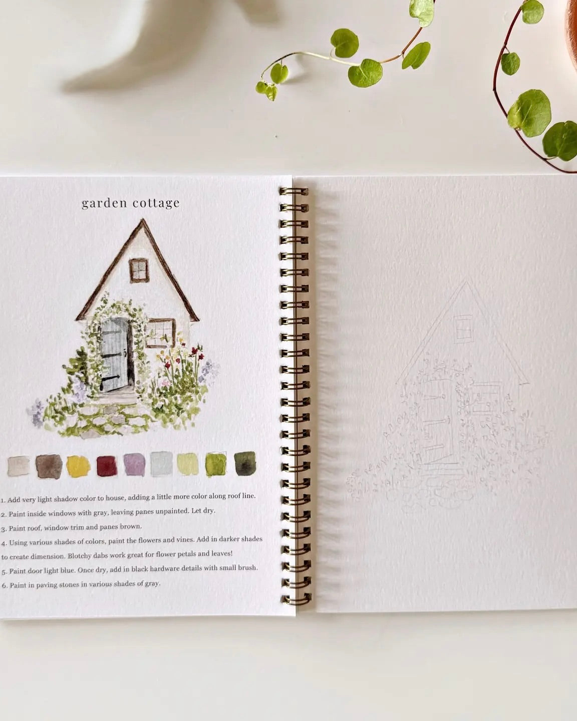 Open Garden watercolor workbook by Emily Lex showing a garden cottage painting example with step by step instructions and a sketch page to paint