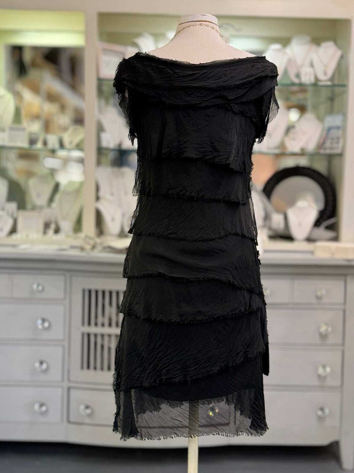 Back view of the Gianna short Italian silk dress in black at Ardor Boutique, showing flowing asymmetrical silk tiers and a sheer layered hem.