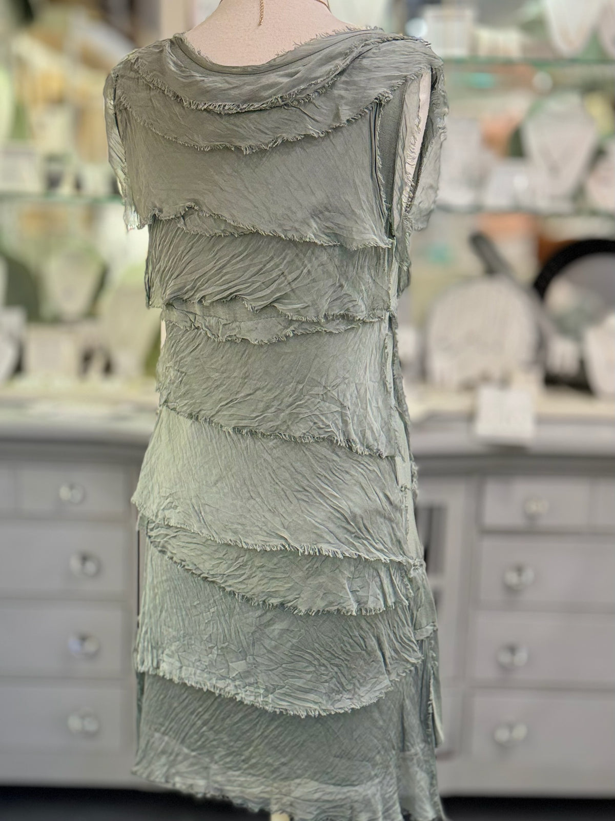 Back view of the Gianna olive Italian silk dress at Ardor Boutique, showing layered silk tiers, textured fabric, and delicate frayed edges.