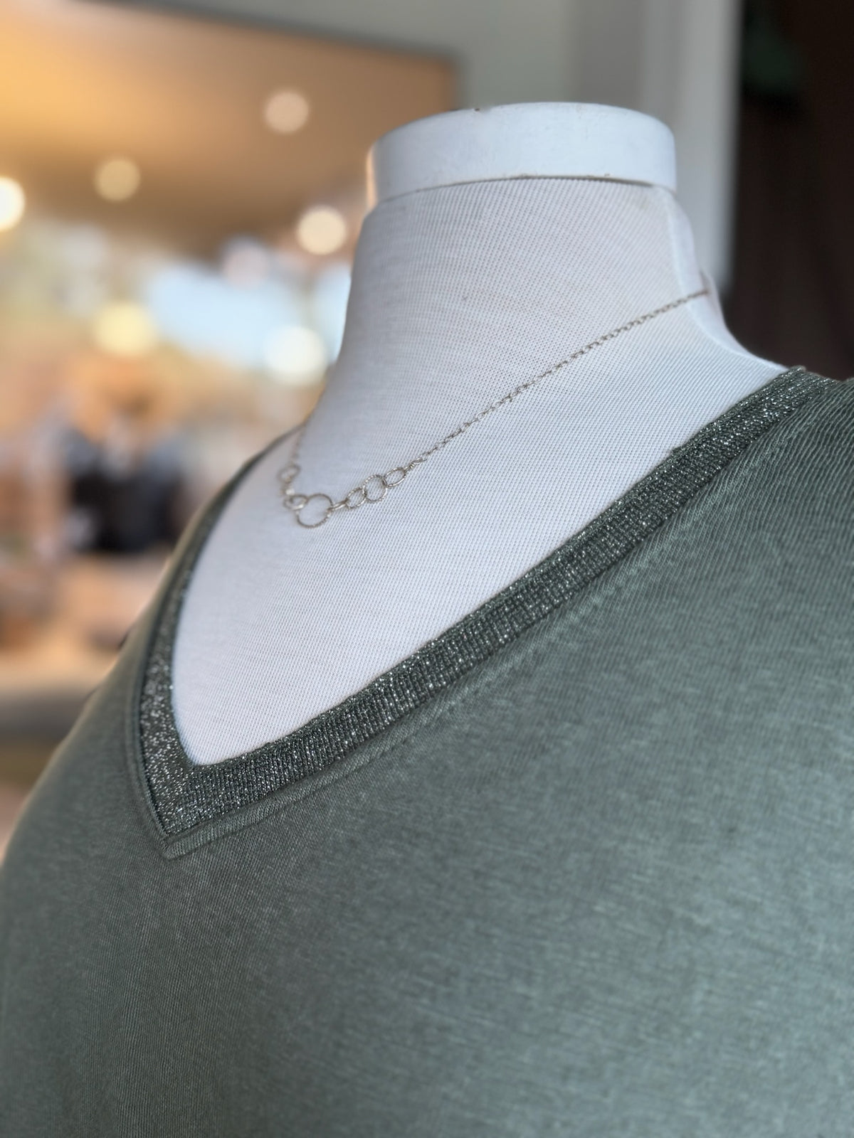 Close-up of the Grace Batwing Top in olive showing the V-neckline finished with subtle silver sparkle threading at Ardor Boutique.