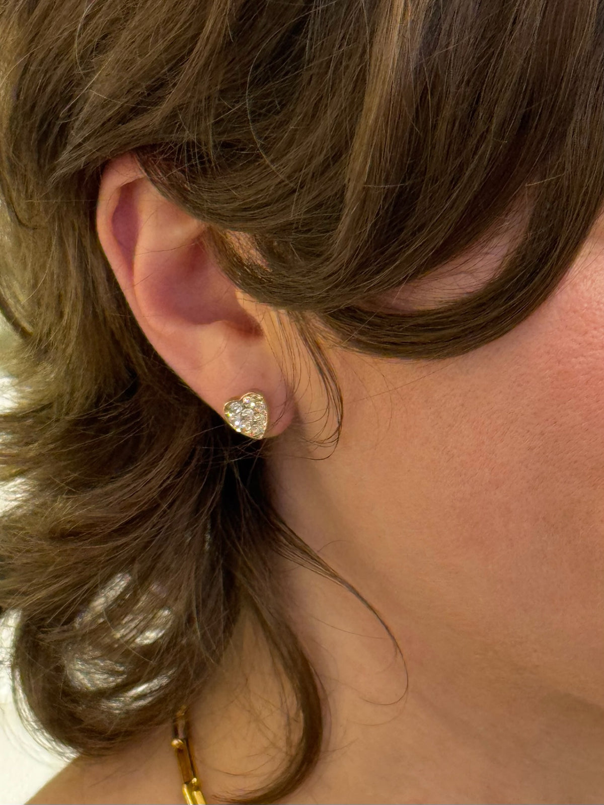 Sparkly gold heart studs being worn
