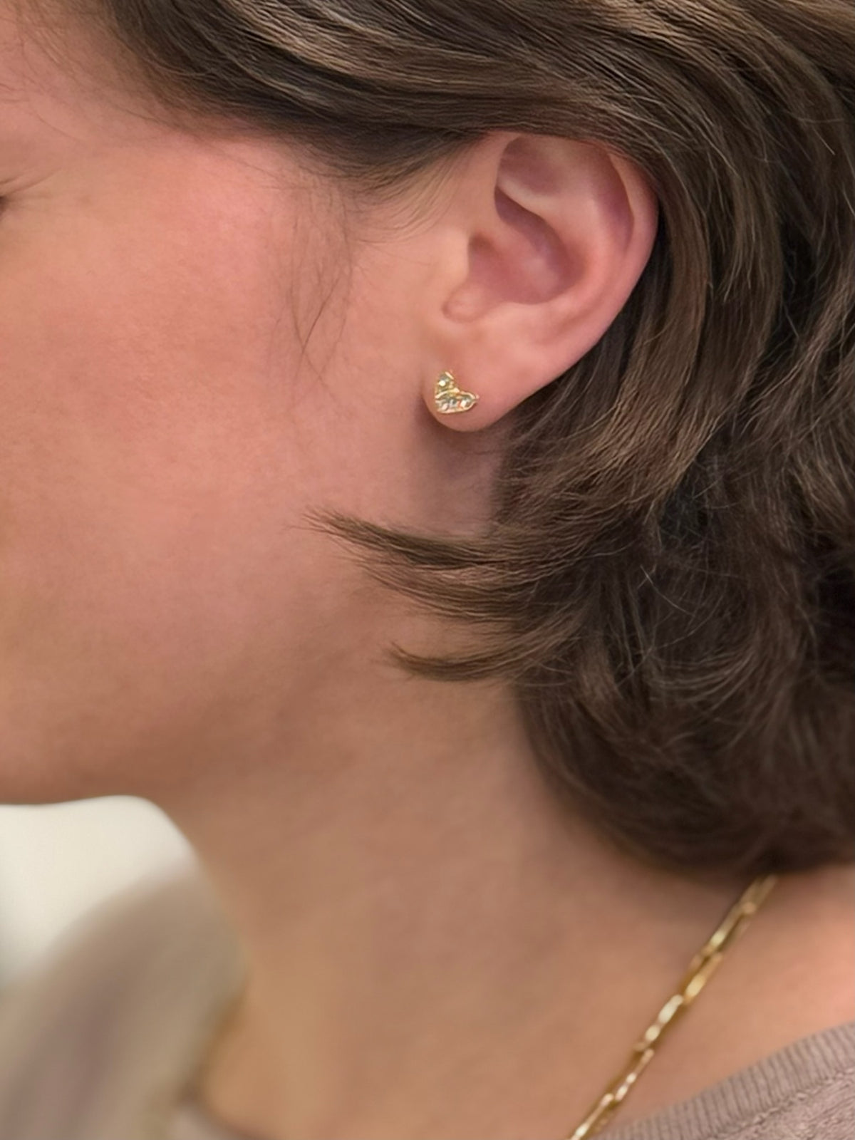 Pair of sparkly heart-shaped stud earrings being worn