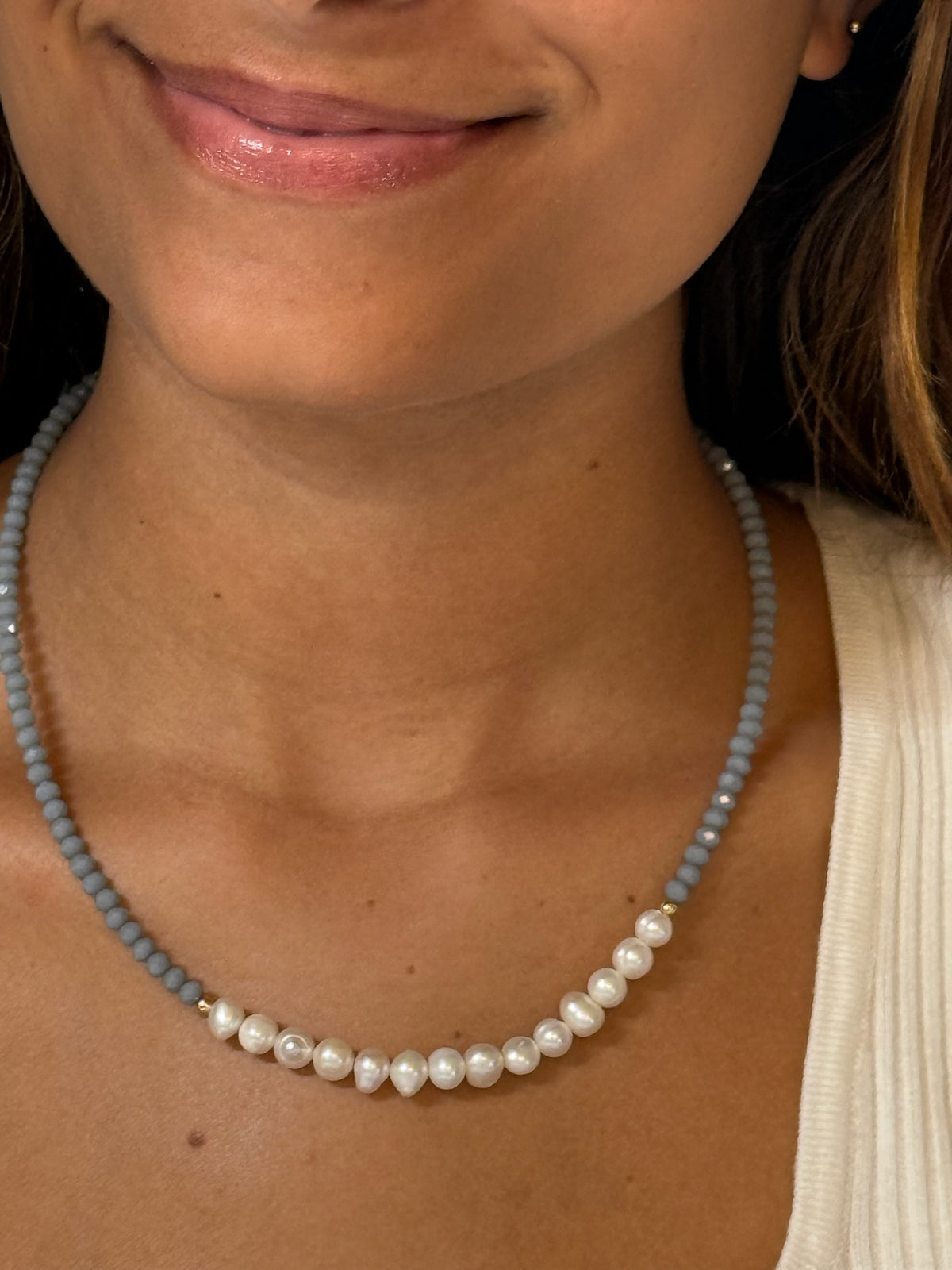 A pale blue necklace with pearls showed on a model 