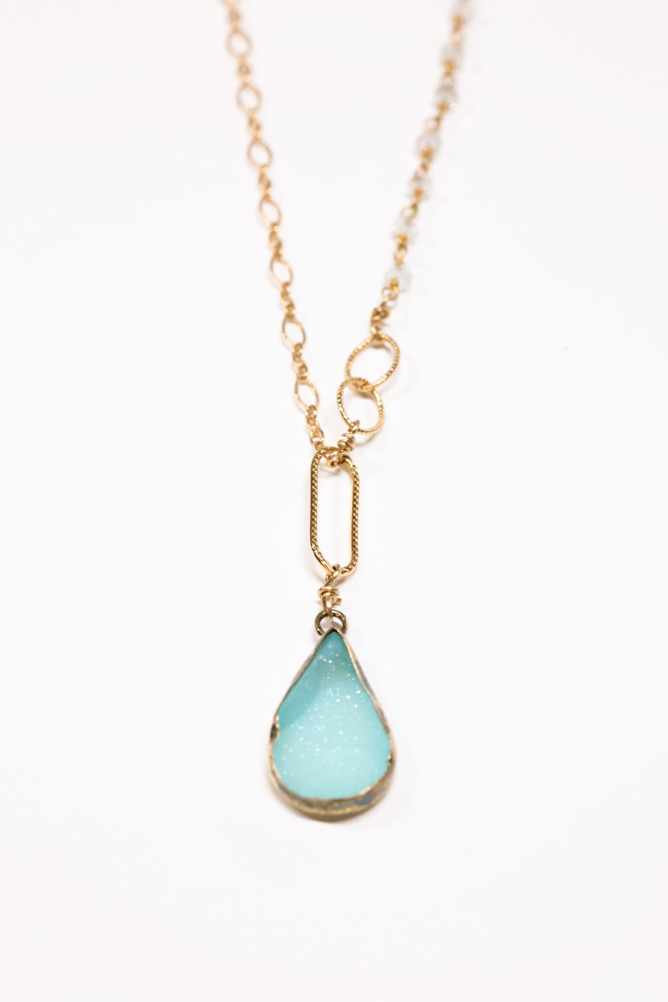 Aquamarine teardrop druzy with tiny quartz necklace flat lay.