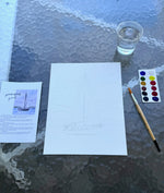 “Peaceful Sail watercolor painting kit setup with sailboat outline on watercolor paper, instruction card, paintbrush, paint palette, and cup of water on a glass table.”