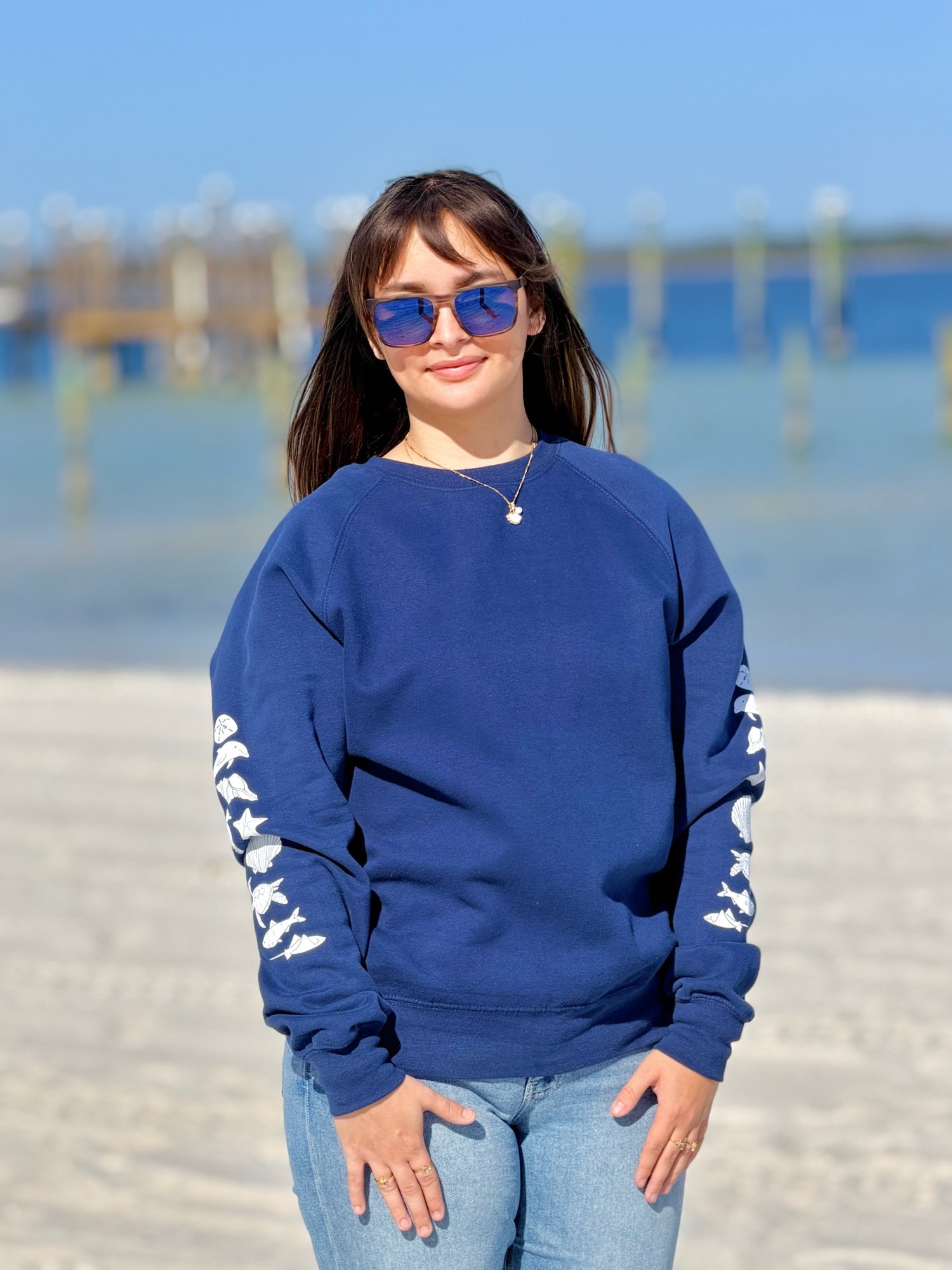 Woman wearing navy coastal crewneck sweatshirt with white sea life sleeve artwork, relaxed fit by Ardor