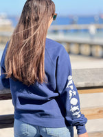 Person wearing a blue hoodie with a design on the back, standing outdoors.