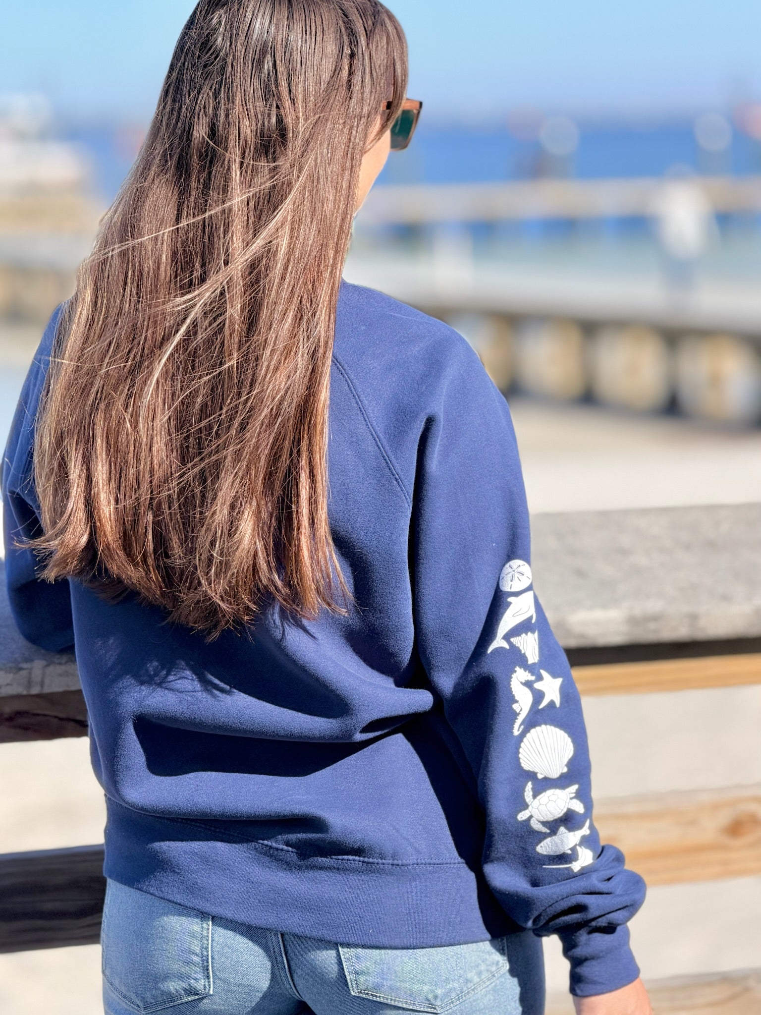 Person wearing a blue hoodie with a design on the back, standing outdoors.