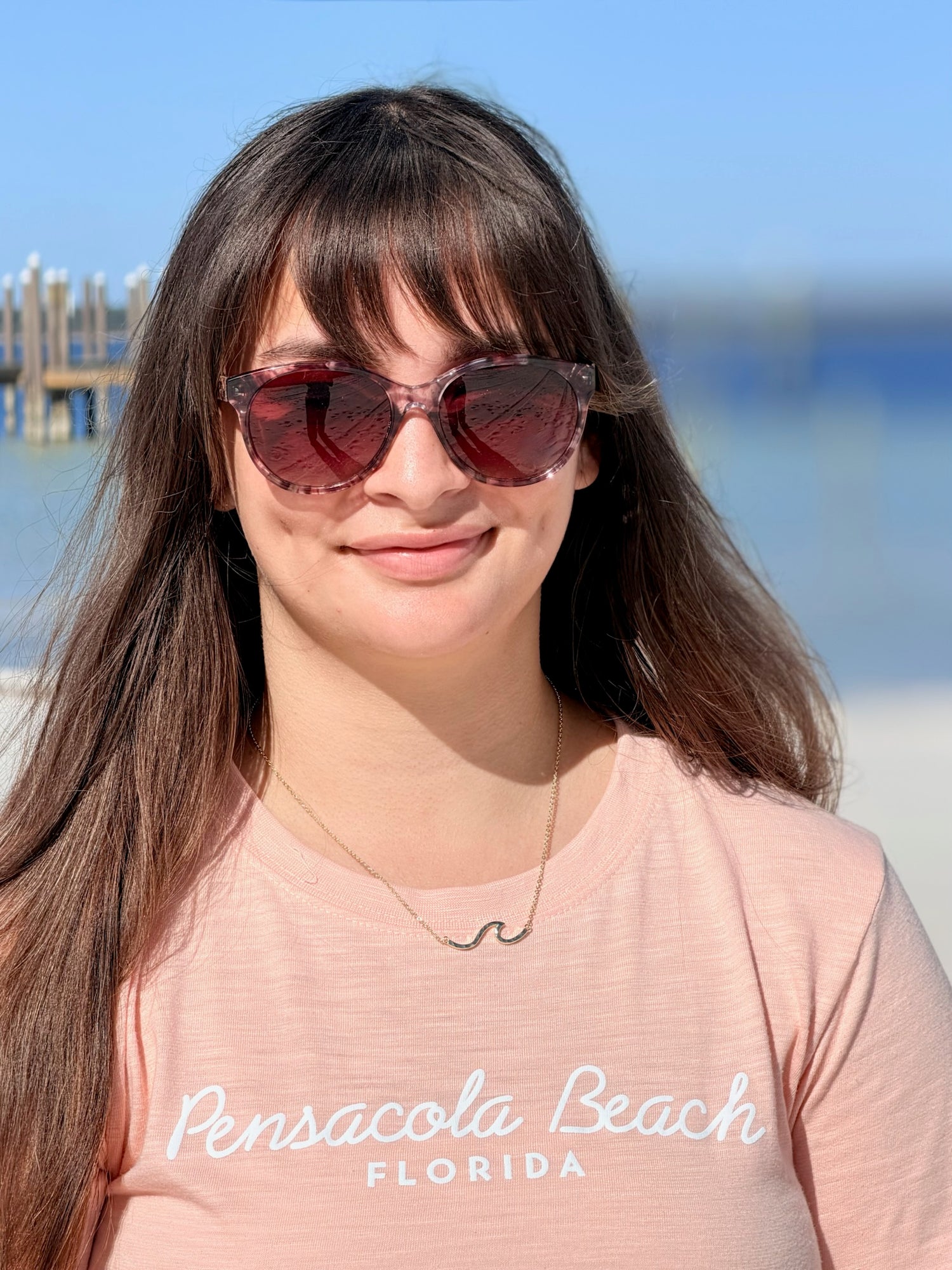 gold over sterling silver wave necklace worn on an adjustable chain, shown on model at the beach.