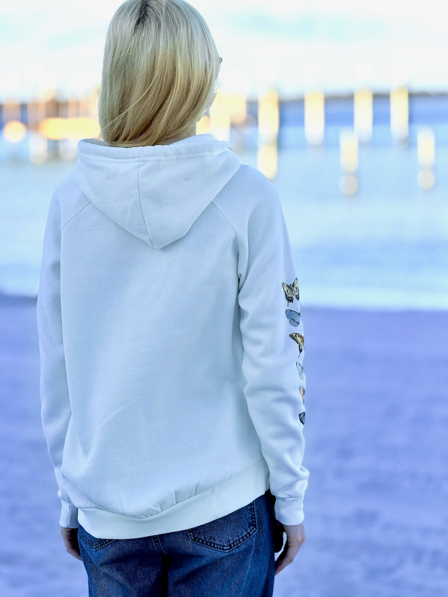 Person wearing a light gray hoodie with a scenic background