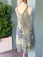 Lightweight sleeveless dress in olive with navy palm leaf pattern and soft drape, shown on a mannequin.