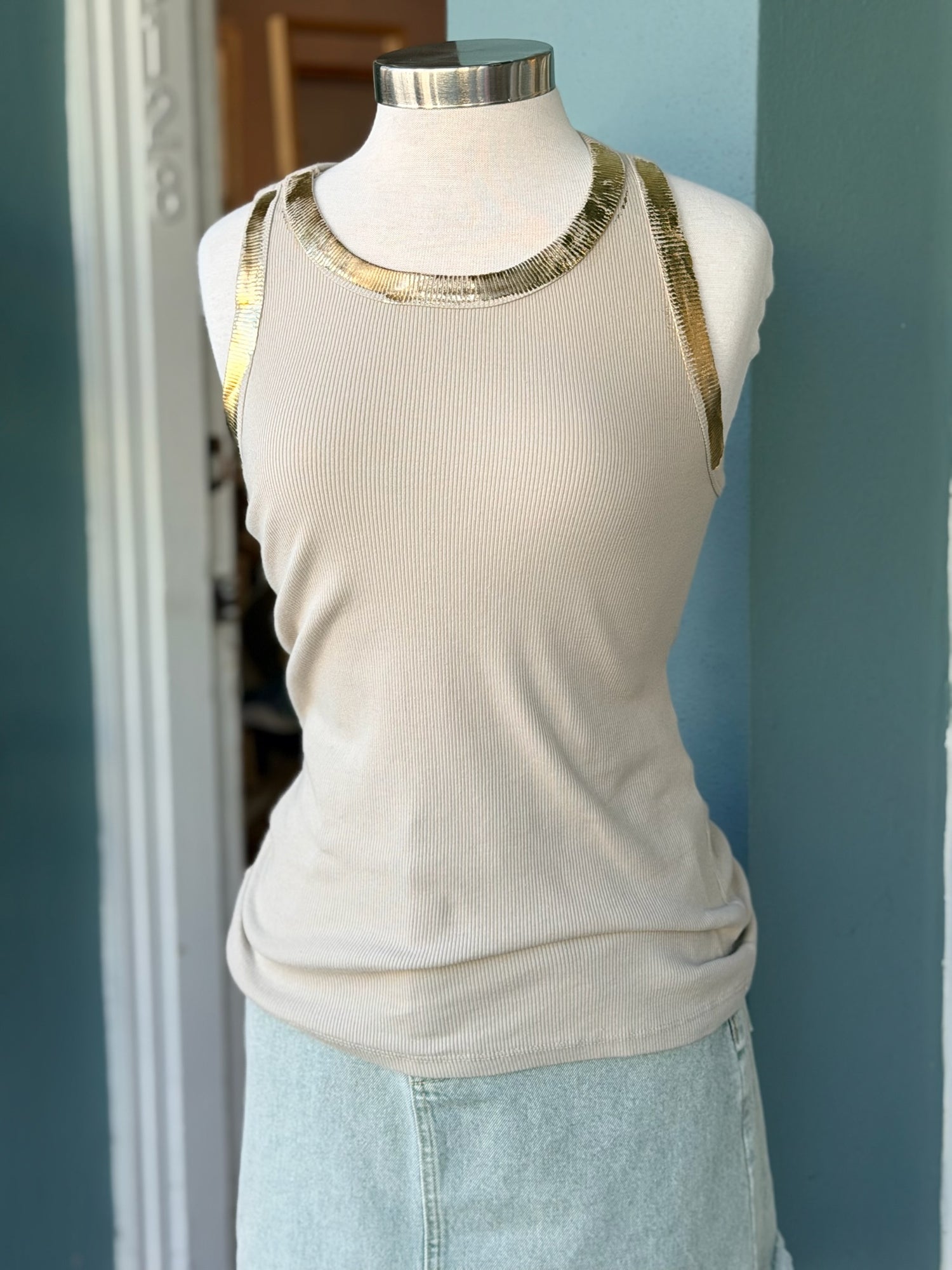 Beige ribbed sleeveless tank top with metallic gold trim along the neckline and arm openings