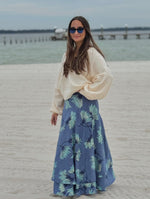 Model wearing layered skirt with a soft aqua base with blue floral print, paired with a cream sweater