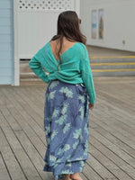 Model wearing layered skirt with a soft aqua base with blue floral print, paired with an aqua sweater back view