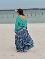 Model wearing layered skirt with a soft aqua base with blue floral print, paired with an aqua sweater side view