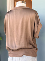 Taupe short-sleeve blouse on a mannequin against a neutral background